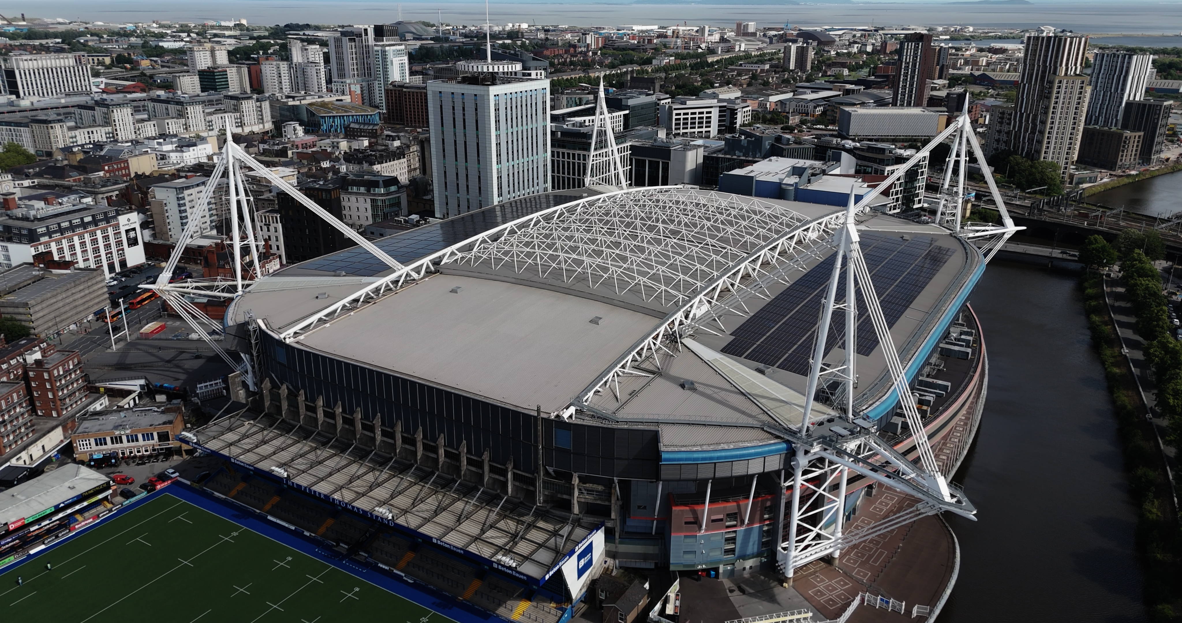 Aerial view of Principality Stadium in Cardiff showing solar panels installed across the stadium roof, surrounded by the city skyline. Aerial view of Principality Stadium in Cardiff showing solar panels installed across the stadium roof, surrounded by the city skyline.